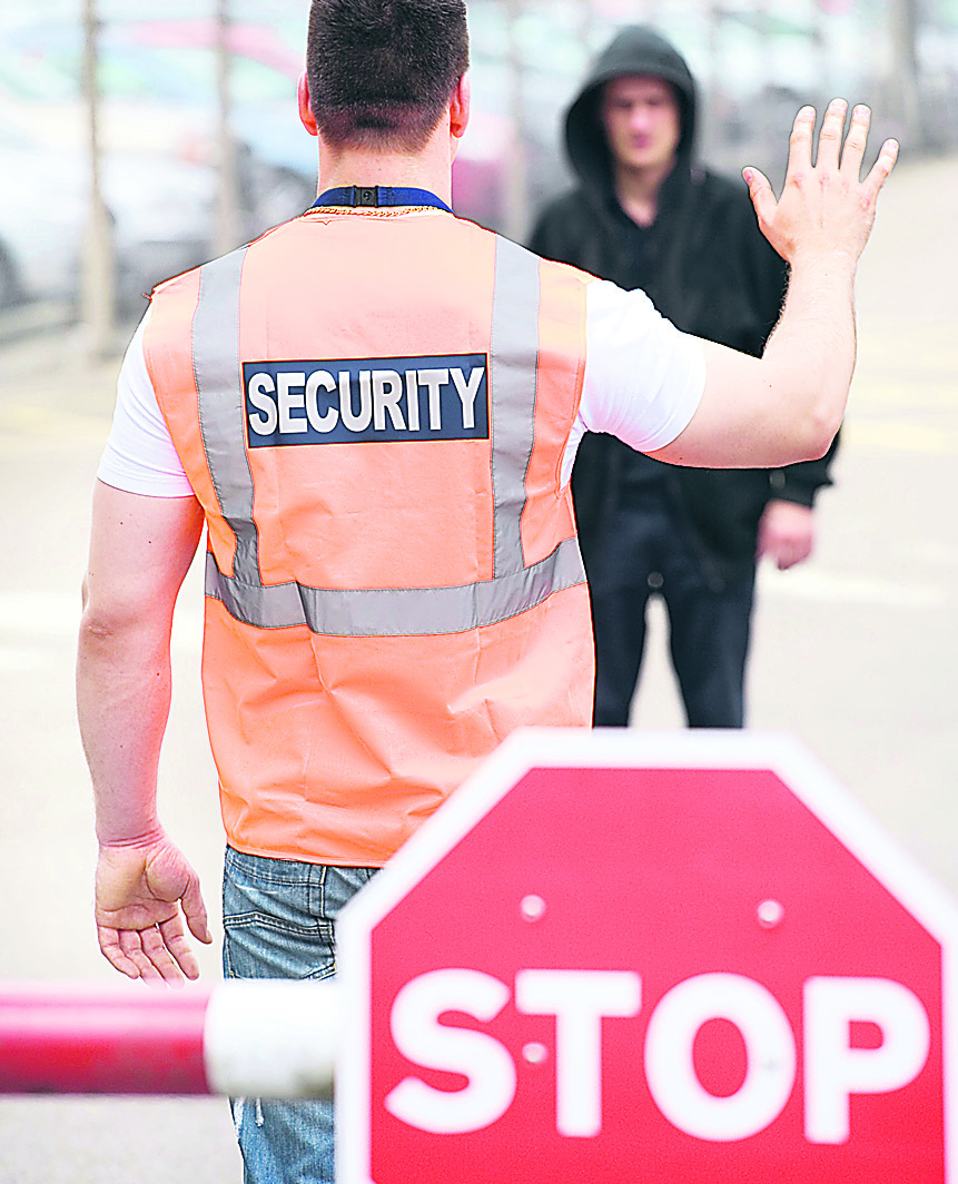  Ein Sicherheitsmann hält einen Menschen vor einem Bahnübergang auf. Online geht es um Datensicherheit im Internet