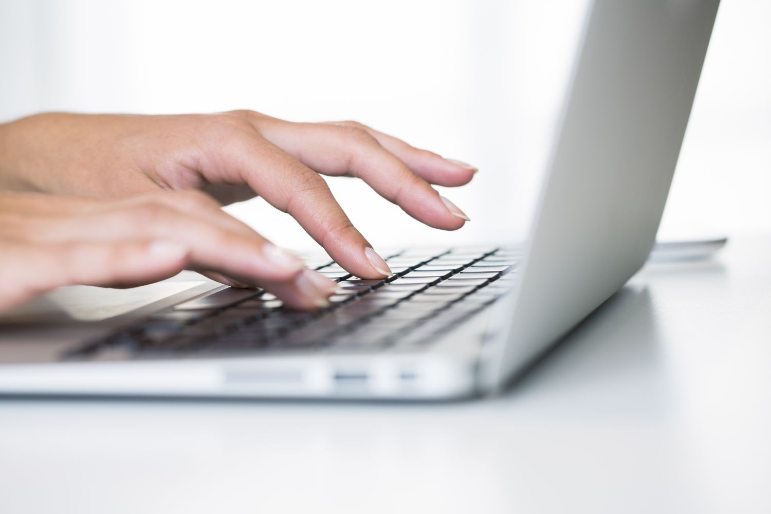 Eine Frau tippt auf der Tastatur ihres Laptops 
